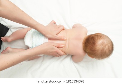 The Baby Is 5 Months Old, Lying On His Tummy. Mom Gives Back Massage To The Child, For Its Development. Children's Gymnastics And Exercises. Top View