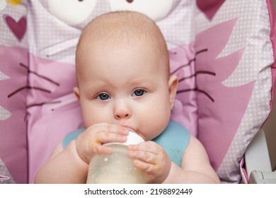 Baby 6 Months Old Sits And Drinks Milk From A Bottle