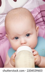 Baby 6 Months Old Sits And Drinks Milk From A Bottle