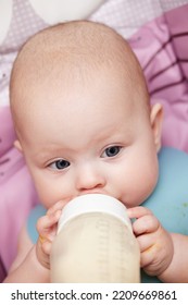 Baby 6 Months Old Sits And Drinks Milk From A Bottle