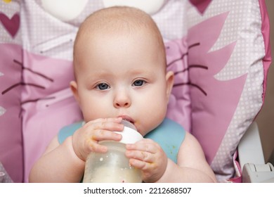 Baby 6 Months Old Sits And Drinks Milk From A Bottle