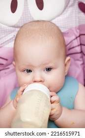 Baby 6 Months Old Sits And Drinks Milk From A Bottle