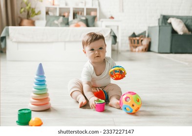 baby 6-9 months old playing with a colorful rainbow toy pyramid sitting in a white sunny bedroom. Toys for small children. Children's interior. A child with an educational toy.