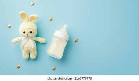 Baby accessories concept. Top view photo of knitted bunny toy milk bottle and gold stars on isolated pastel blue background with copyspace - Shutterstock ID 2168778775