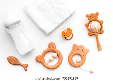 Baby Accessories. Wooden Toys, Pacifier And Bottle On White Background Top View