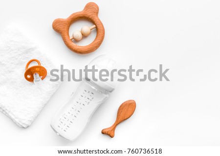 Baby accessories. Wooden toys, pacifier and bottle on white background top view copyspace
