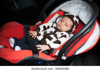 Baby Asleep Buckled Into Red Car Seat. 