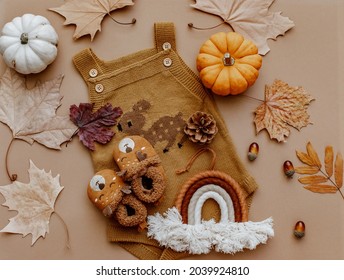 Baby Autumn Wear Clothes With Pumpkins And Leaves On Brown Background. Top View. Cute Warm Kid Autumn Bodysuit And Booties. Autumn Baby Shower