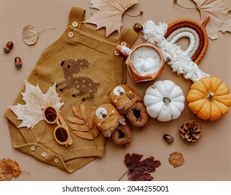 Baby Autumn Wear Clothes With Pumpkins And Leaves On Brown Background. Top View. Cute Warm Kid Autumn Bodysuit And Booties. Autumn Baby Shower