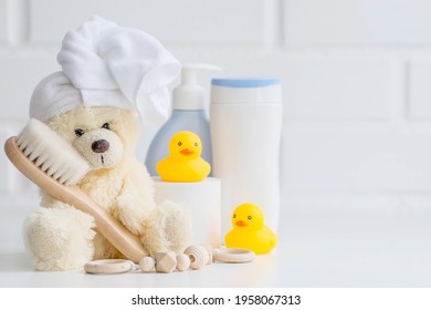 Baby bath accessories, children care, a yellow bear with a towel on its head, a brush and bottles of shampoo.