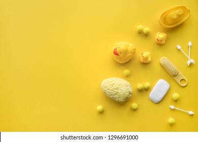 Baby bathing flat lay. Children cosmetics set: rubber duck, towel, shampoo, soap, scissors, sponge, hair and tooth brush on yellow top view copy space for text. 
