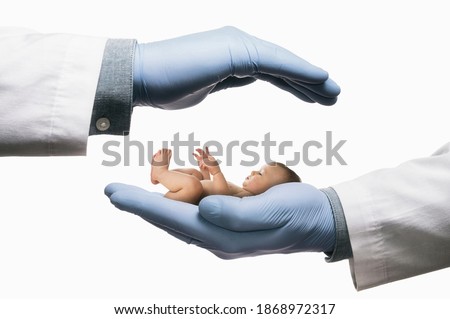 Baby between two palms of doctor hands on white isolated background. In vitro fertilization. Concept