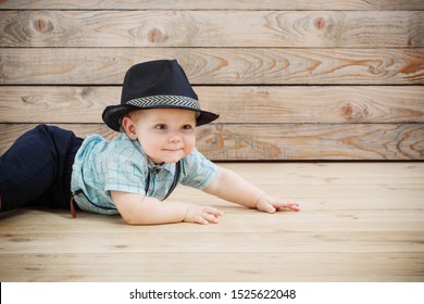 Baby In Black Hat, Shirt And Suspenders Shorts  On Wooden Background