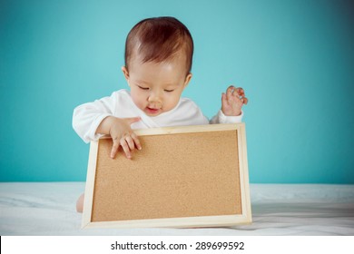 Baby with blank board with copy space and sitting on the bed in the blue bedroom, Baby healthy and preschool concept