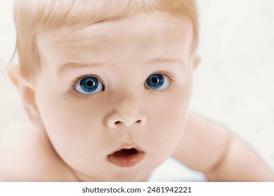 Baby with blue eyes gazes innocently and curiously, radiating happiness and health, capturing childhood wonder in a studio portrait - Powered by Shutterstock