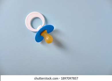 Baby blue pacifier on a blue background, place for an inscription