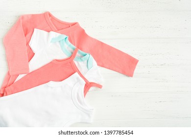 Baby bodysuit clothes over white wooden background. Copy space. Flat lay style. Pink and white wearing. Children fashion concept - Shutterstock ID 1397785454