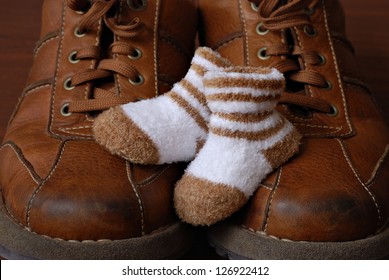 Baby booties nestled on top of parent's well worn leather shoes.  Macro with shallow dof. - Powered by Shutterstock