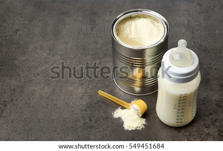 Baby bottle and milk powder on dark grey table