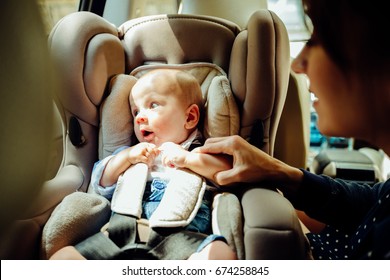 Baby Boy In Car Seat For Safety, Looking Outside While His Mom Sitting Near Him.