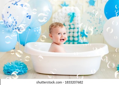 baby boy celebrates birthday 1 year in a bath with balloons, bathing the baby in a bath with foam, soap bubbles and blue balloons