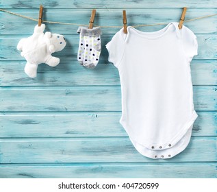Baby boy clothes and white toy bear on a clothesline