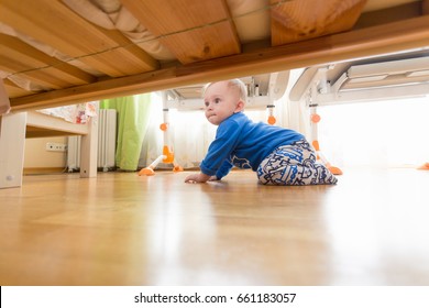 Baby Boy Crawling On Floor And Looking Under The Bed