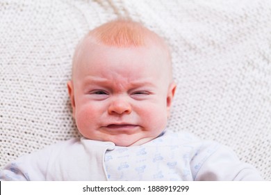 Baby Boy Crying In Bed. Newborn With Upset Unhappy Mean Face