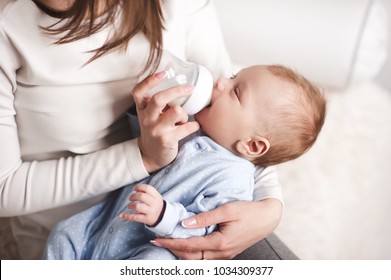 Baby Boy Drinking Milk From Bottle Holding By Mother. Healthy Nutrition. 