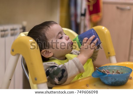 baby boy drinks from a drinker