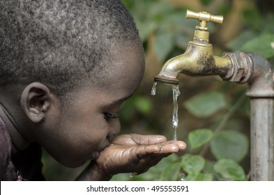 Мальчик пьет воду из крана в саду