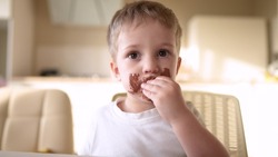 Baby Boy Eat Chocolate. Dirty Little Baby Kids In The Kitchen Eating Chocolate In The Morning. Happy Family Eating Sweets Kid Dream Concept. Lifestyle Baby Dirty Face Eating Chocolate Cocoa