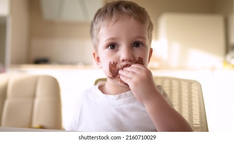 Baby Boy Eat Chocolate. Dirty Little Baby Kids In The Kitchen Eating Chocolate In The Morning. Happy Family Eating Sweets Kid Dream Concept. Lifestyle Baby Dirty Face Eating Chocolate Cocoa