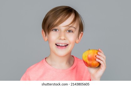 Baby boy eating apple and smiling. Boy smiles and has healthy white teeth. Little boy eating apple. Boy apples showing. Child with apples. Portrait of cute little kid holding an apple.