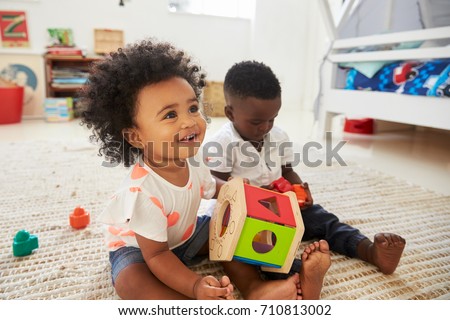 Baby Boy And Girl Playing With Toys In Playroom Together