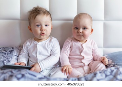 Baby Boy And Girl Twins On Parents Bed In The Early Morning