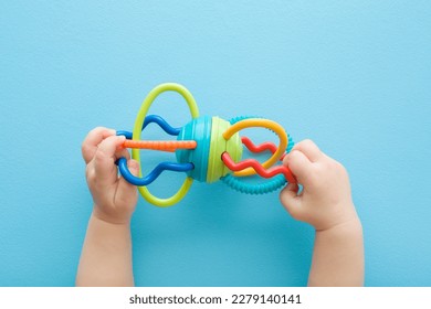 Baby boy hands playing with colorful rattle on light blue table background. Pastel color. Closeup. Point of view shot. Toys of development for infant. - Powered by Shutterstock