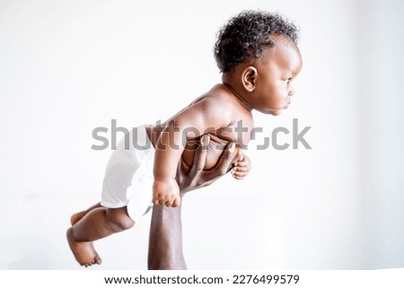 Baby boy held by his father's hands on white background
