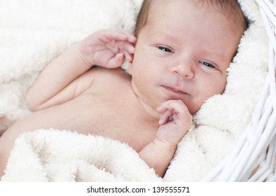 Baby Boy Lying In Basket With His Eyes Open On The Blanket