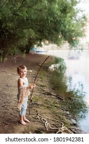 Baby Boy On A Sandy Beach Near The River Holding A Fishing Rod And A Fisherman, Fishing Net