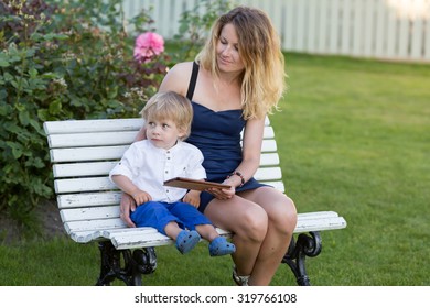 Baby Boy Outdoors Sitting With Mom In The Garden With IPad.