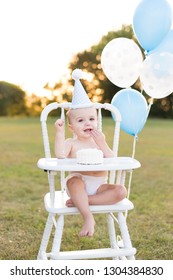 Baby Boy Outside In High Chair With Balloons On Birthday