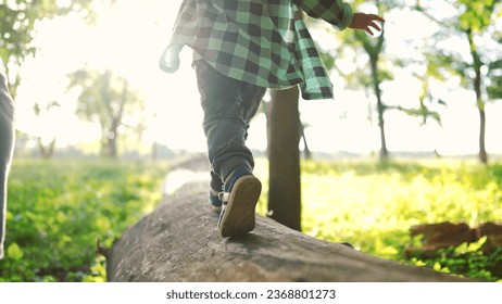 baby boy play in the forest park. close-up child feet walk on a fallen tree log. happy family kid dream concept. a child in sneakers walk on fallen tree in park lifestyle - Powered by Shutterstock