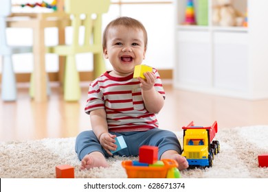 Baby boy playing with his colorful toys on floor at home. - Powered by Shutterstock