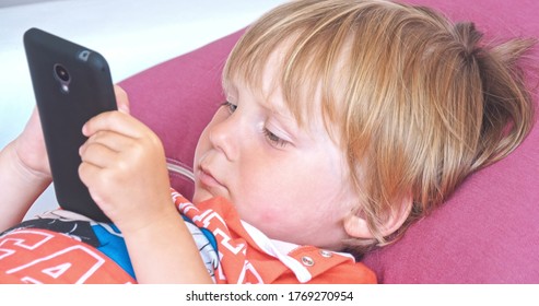 baby boy playing with mobile phone, new digital technologies in the hands of a child. Portrait of toddler with smartphone