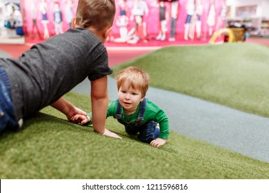 Baby boy playing on artificial grass hills in toy store. A blond child hides in an synthetic grass. - Powered by Shutterstock