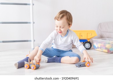 Baby Boy Playing With Wooden Toys At Home On The Floor