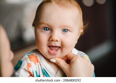 Baby Boy Portrait Looking At Camera. Close-up Mother Hands Open Baby Mouth To Examine First Teeth. Infant Primary Tooth. The Happy Baby Infant With First Tooth.