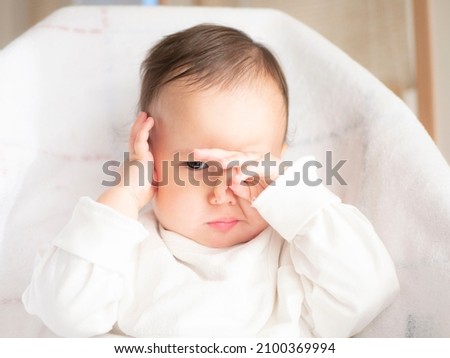 A baby boy rubs his eyes