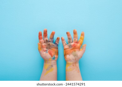 Baby boy showing painted hands in colorful paints on light blue table background. Pastel color. Closeup. Point of view shot. - Powered by Shutterstock